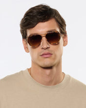 Load image into Gallery viewer, Man wearing brown aviator sunglasses against a light gray background