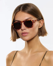 Load image into Gallery viewer, Woman wearing tortoiseshell sunglasses against a plain background
