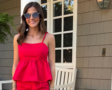 Load image into Gallery viewer, Woman in a red dress standing outside a house