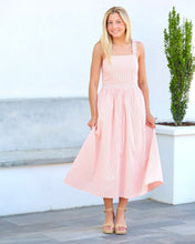 Load image into Gallery viewer, Woman in a pink dress standing outdoors with a white wall and plant in the background