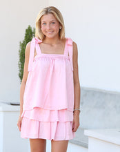 Load image into Gallery viewer, Woman in a pink dress standing outdoors with a white building in the background