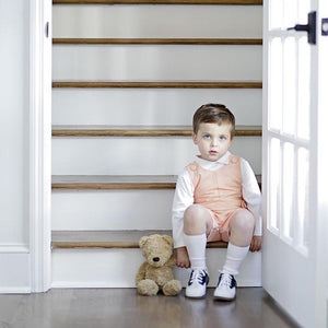 Baby sits on stairs modeling James Island John John in Oyster Point Orange